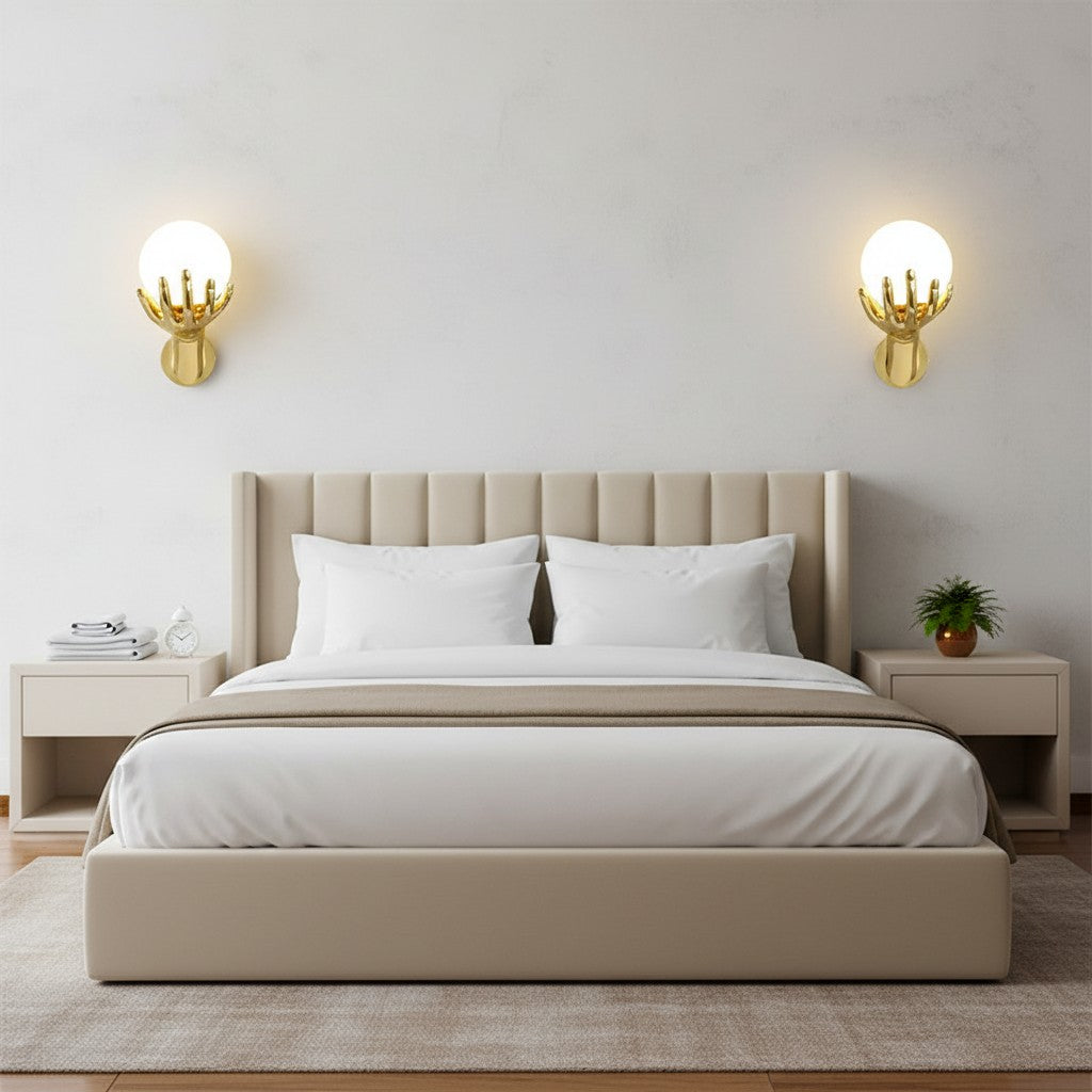 GoldenWatt gold hand-shaped wall sconces with frosted glass globes mounted on a modern bedroom wall above a bed