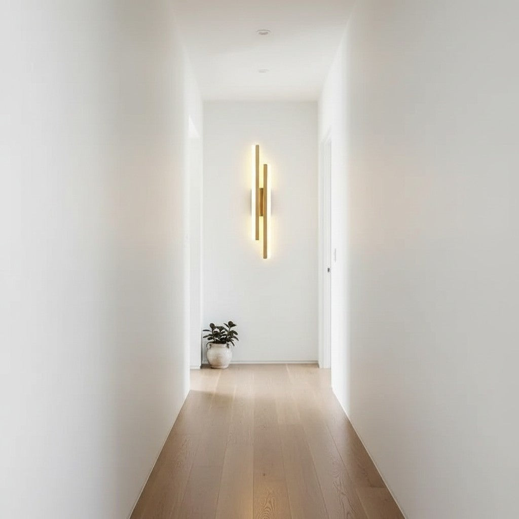 GoldenWatt dimmable gold LED wall sconce mounted in a minimalist white hallway with a potted plant