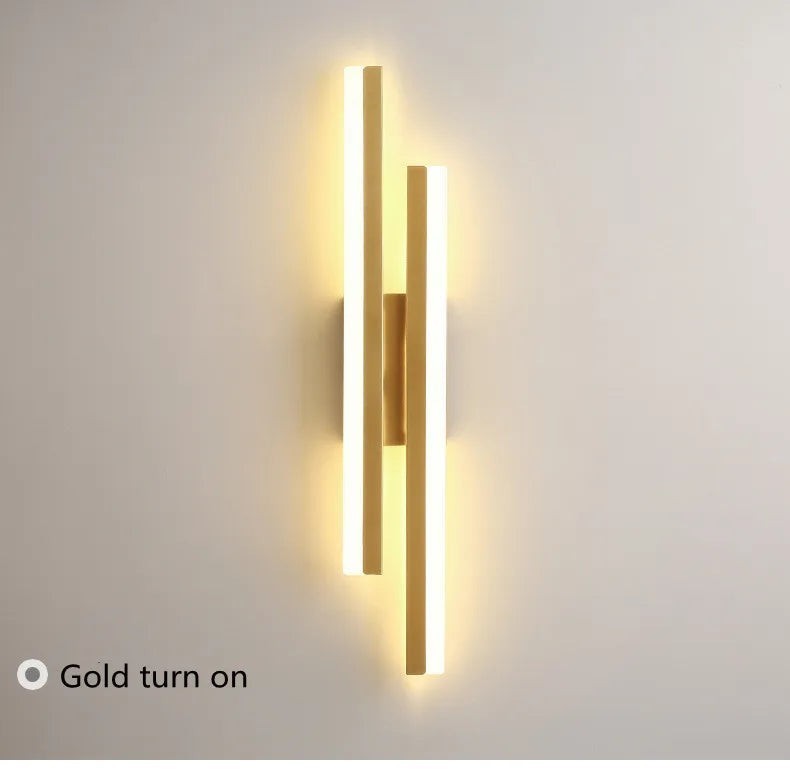 GoldenWatt dimmable gold LED wall sconce with modern iron and acrylic strip design illuminated on a white wall