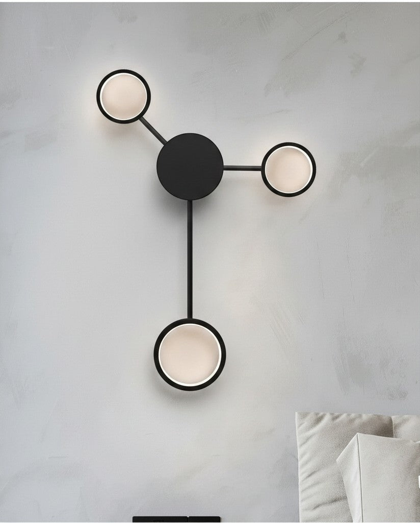 GoldenWatt Nordic minimalist wall lamp with three circular LED heads in black iron, mounted on a light grey wall.