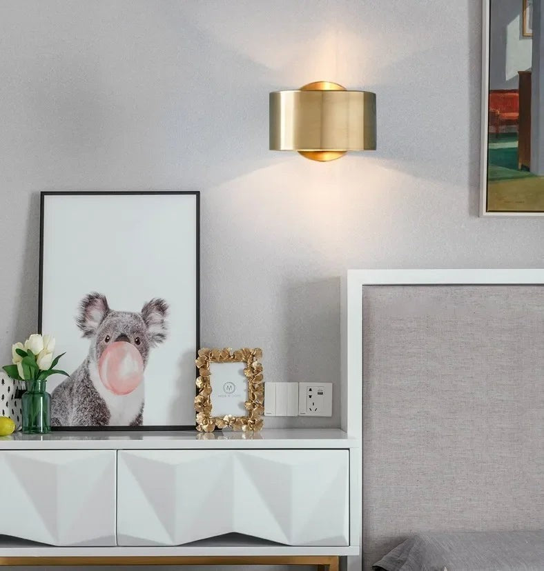 GoldenWatt Nordic gold iron wall sconce mounted above a bedroom nightstand, emitting a warm white glow.