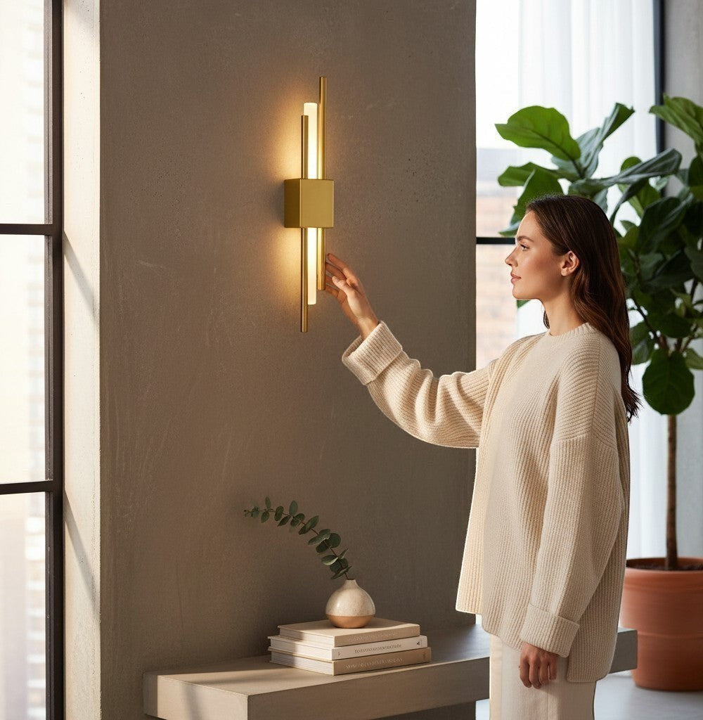 GoldenWatt Nordic LED wall sconce in gold with acrylic detail, being switched on by a woman in a modern living room.