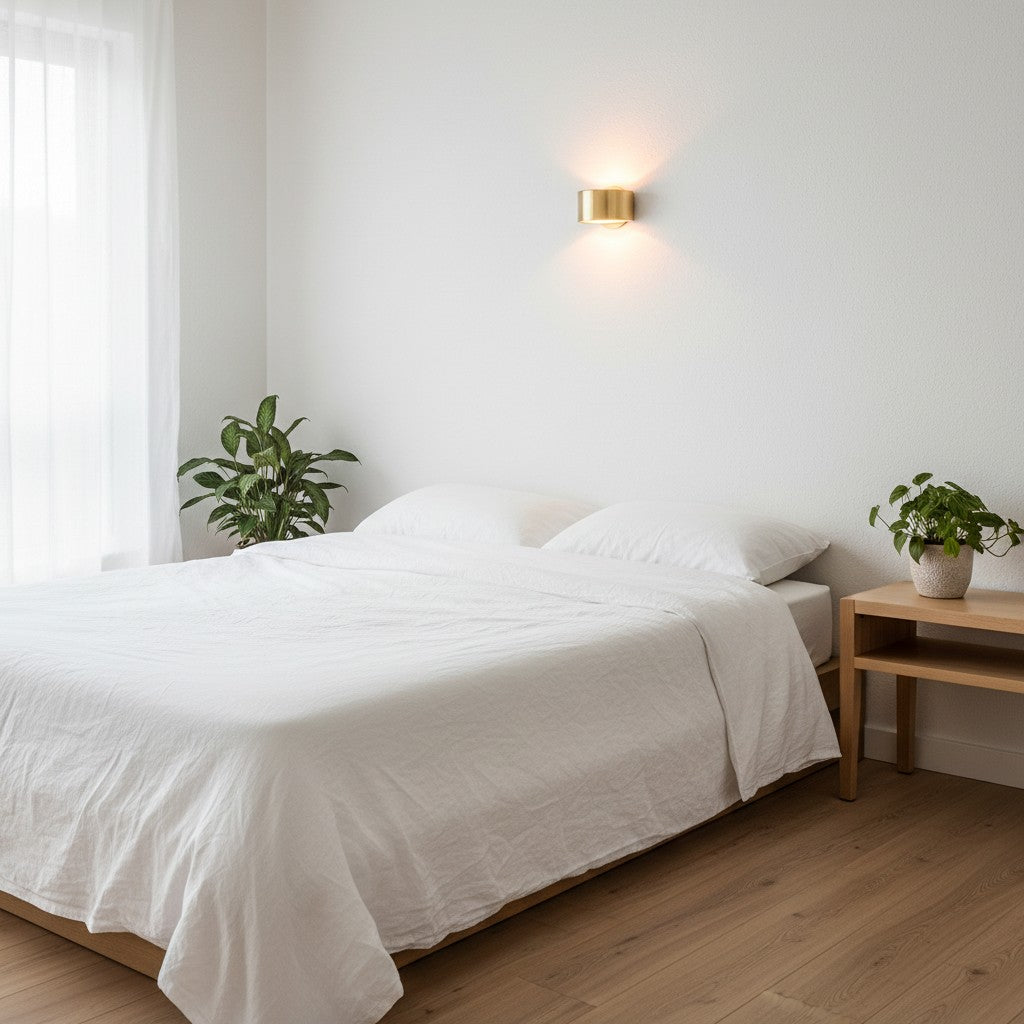 GoldenWatt Nordic gold iron wall sconce emitting warm white light above a minimalist bedroom bed